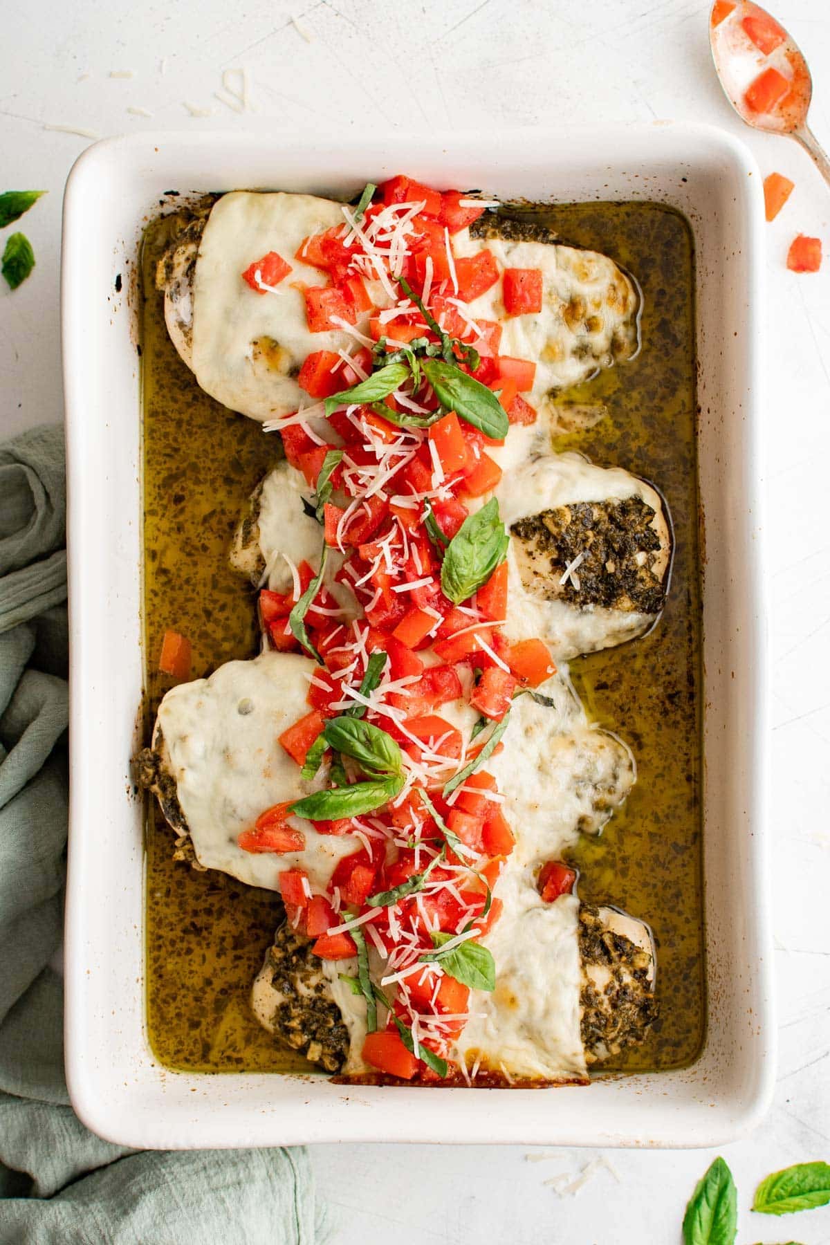 white baking dish with chicken breasts, pesto with cheese