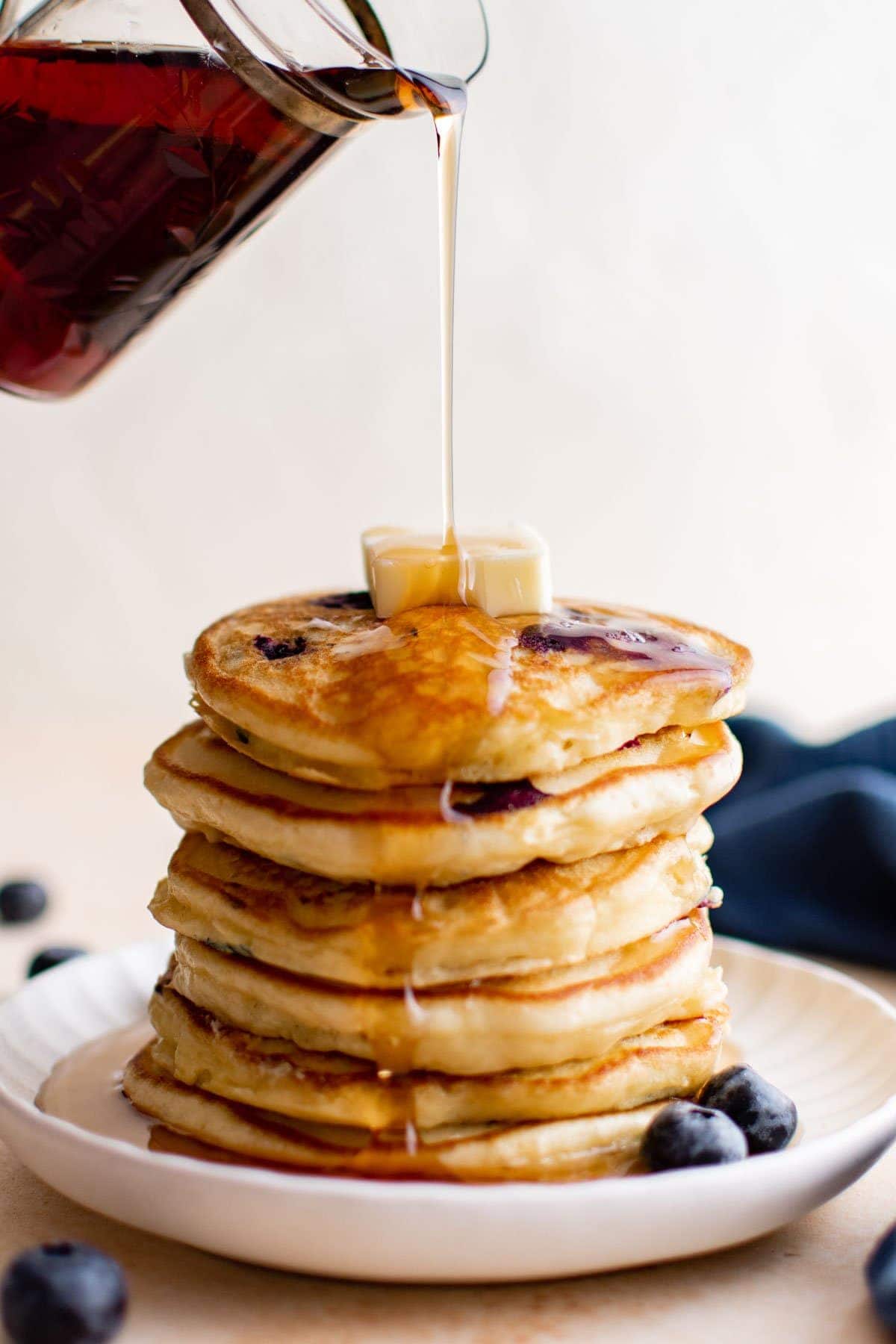 stack of blueberry pancakes with syrup pouring over