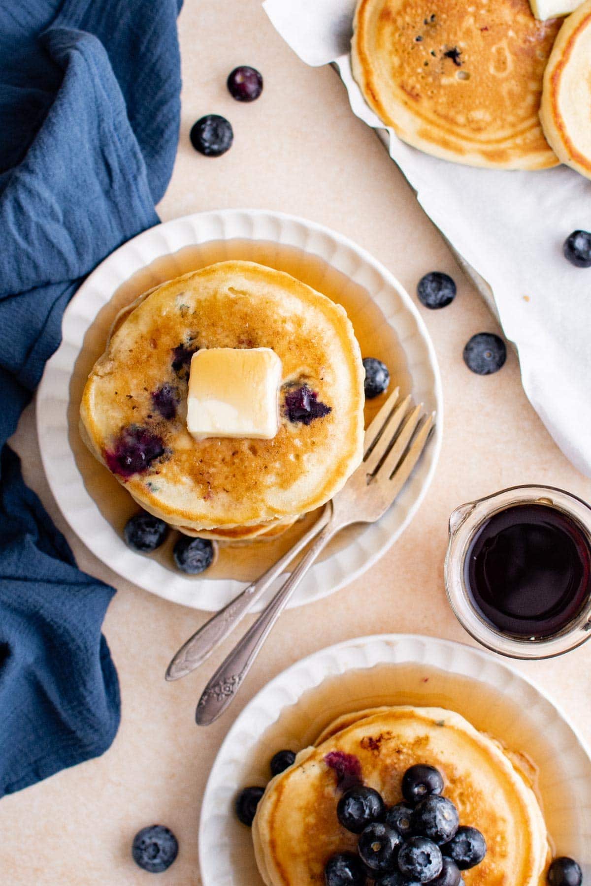blueberry pancakes on white plates with butter