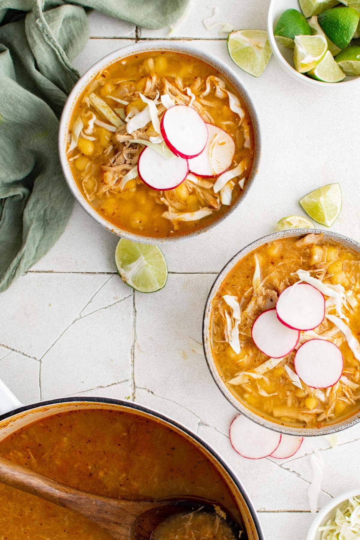 2 bowls of red chicken pozole topped with radishes and cabbage