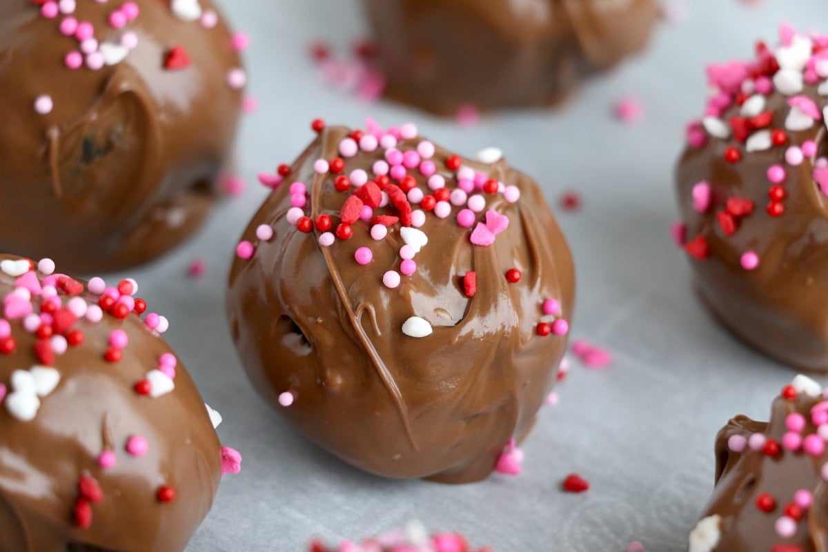 chocolate covered cake balls with pink, red and white sprinkles