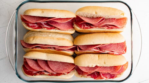 hoagie rolls in a baking dish with salami