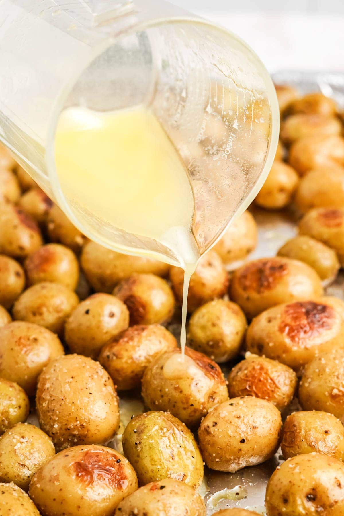 butter being poured over roasted baby potatoes