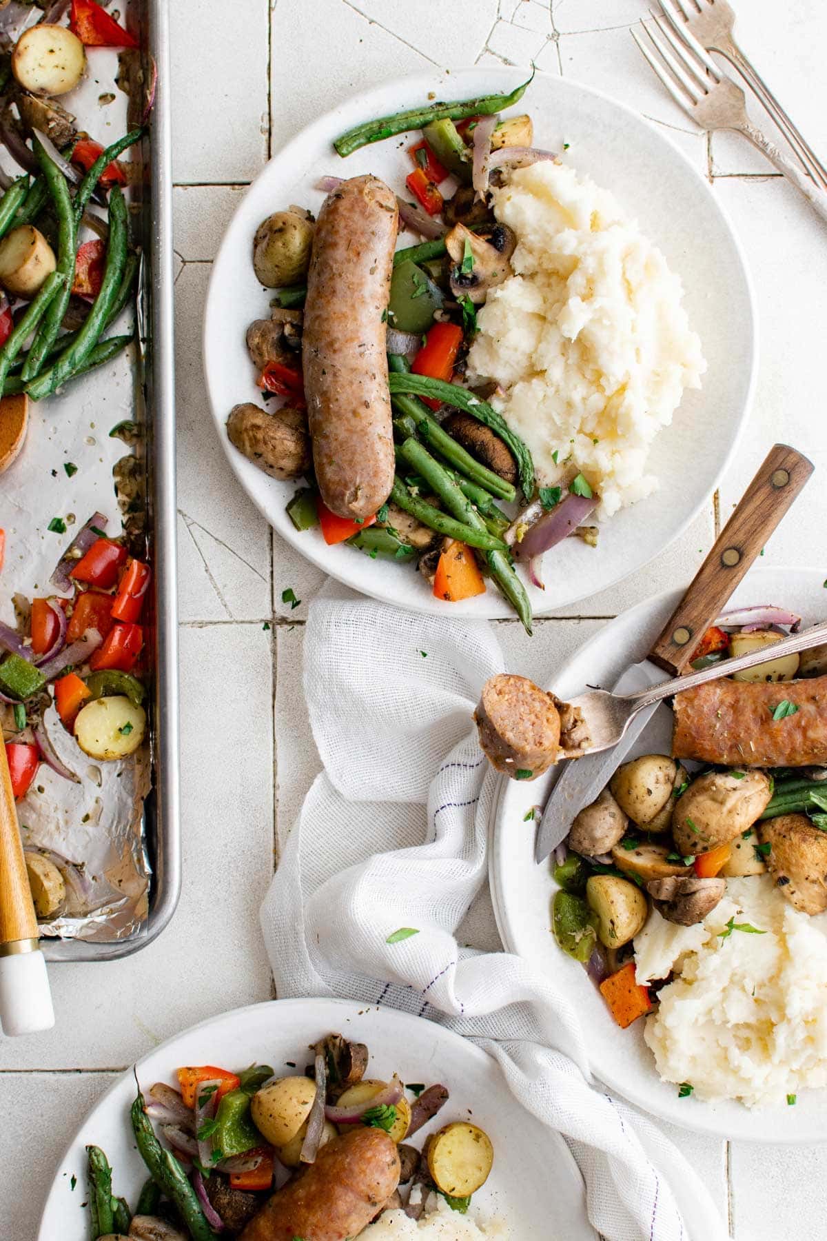 three plates with sausages, vegetables and mashed potatoes