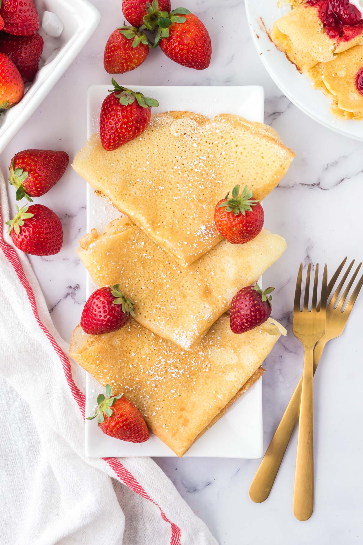 folded swedish pancakes with strawebrries and powdered sugar