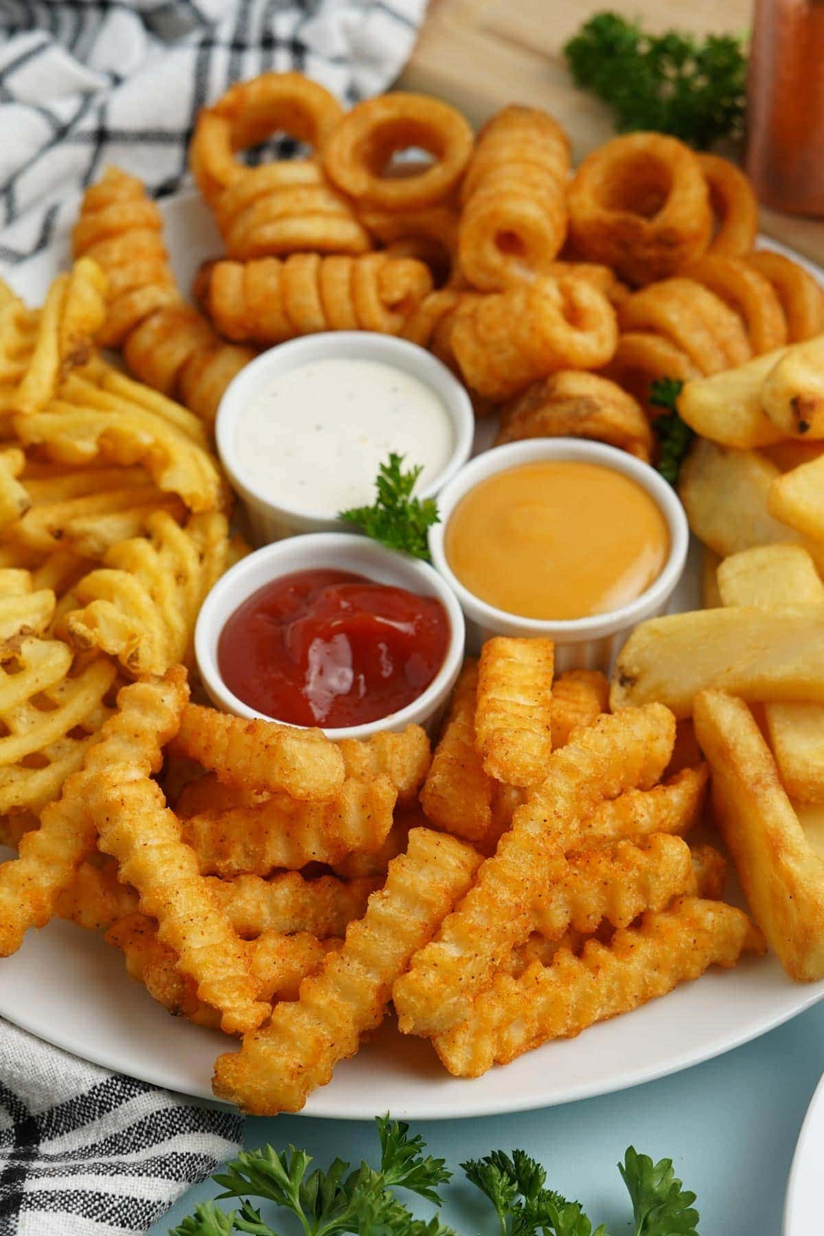 different fries on a platter with dipping sauces