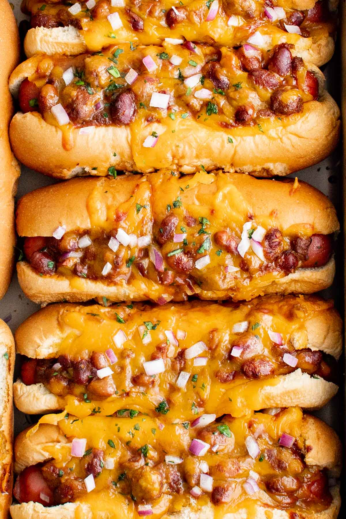 hot dogs with chili, onions in a baking dish