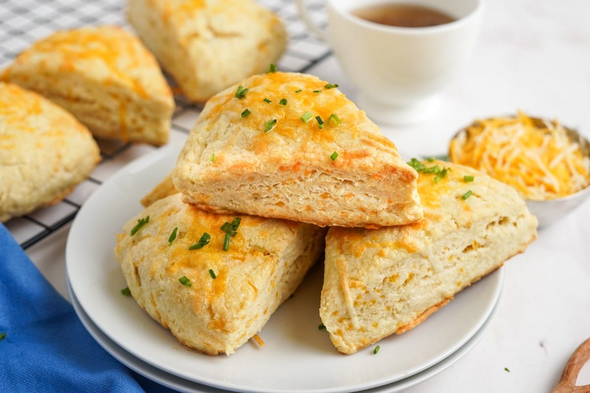 cheese scones stacked on a white plate topped with chives