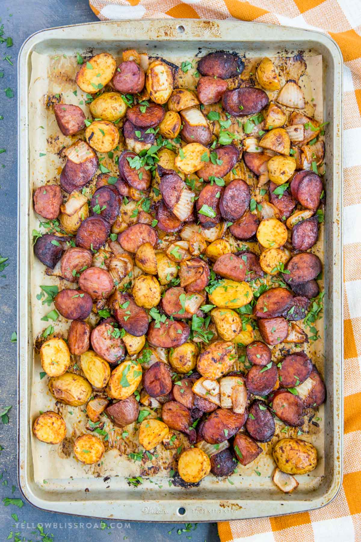 sheet pan with smoked sausage slices, potatoes and onions