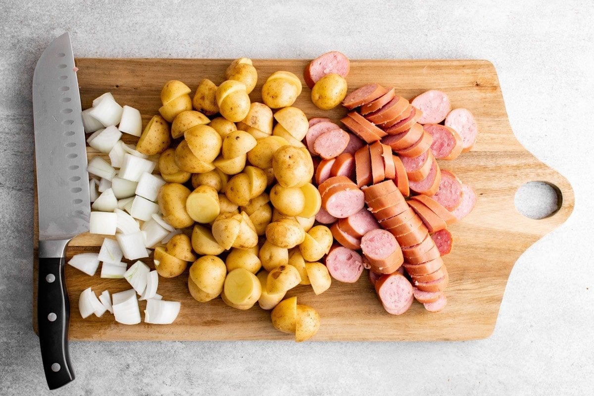 sliced sausage, potatoes and onions on a cutting board