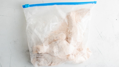 Chicken legs in a plastic bag, coated in flour and seasonings.