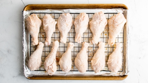 Chicken legs on a wire rack and baking sheet.