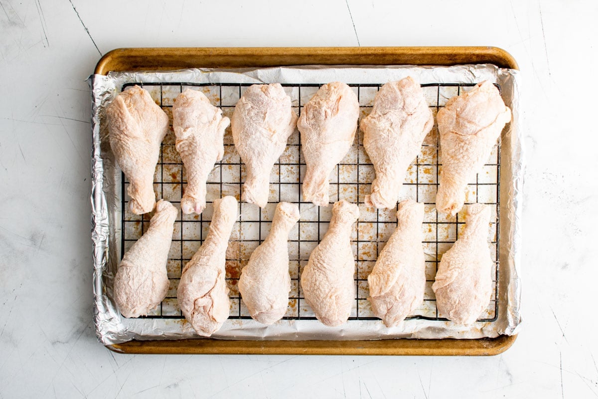 Chicken legs on a wire rack and baking sheet.