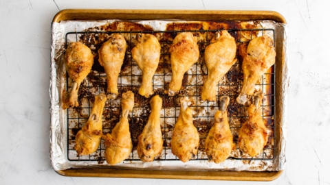 Baked and browned chicken drumsticks on a baking sheet.