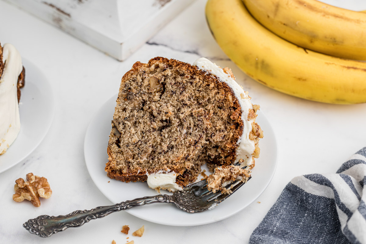 a slice of banana cake on a white plate with a fork