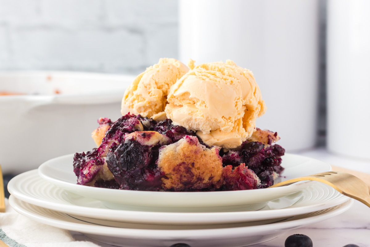 side view of cobbler with blueberries and vanilla ice cream