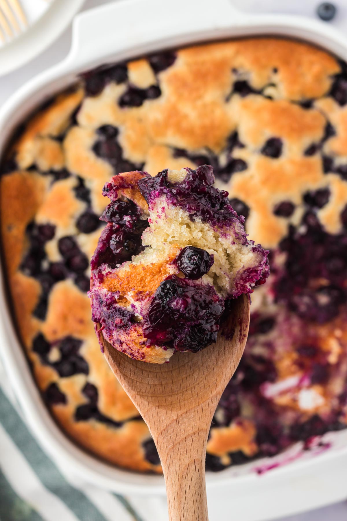 blueberry cobbler, with a scoop sitting on a wooden spoon