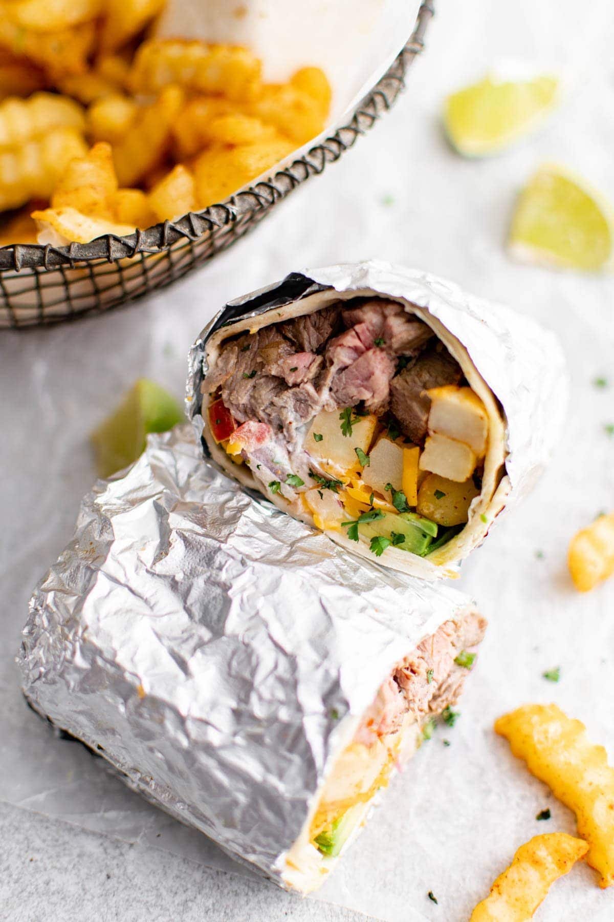 california burrito, wrapped in foil and sliced in half