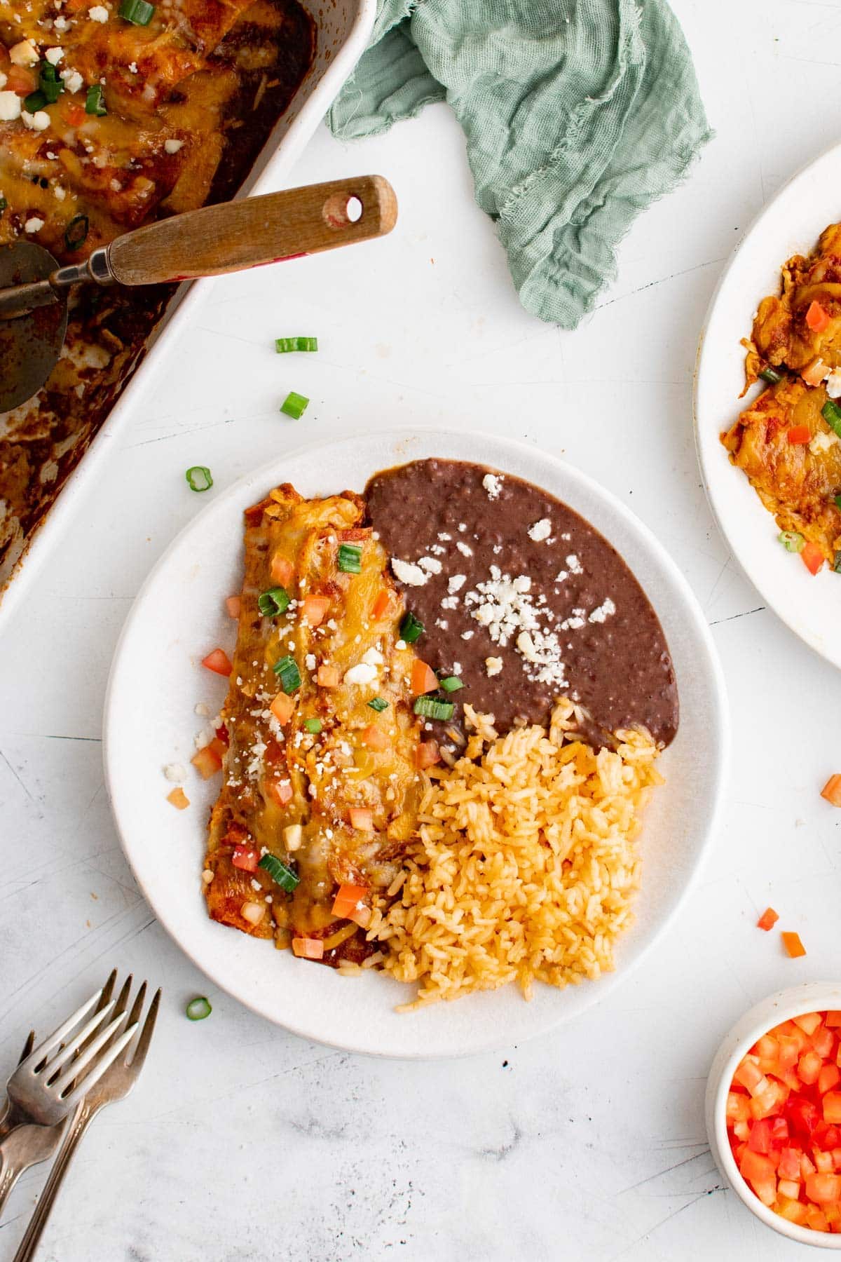 serving of cheese enchilads on a plate with rice and beans