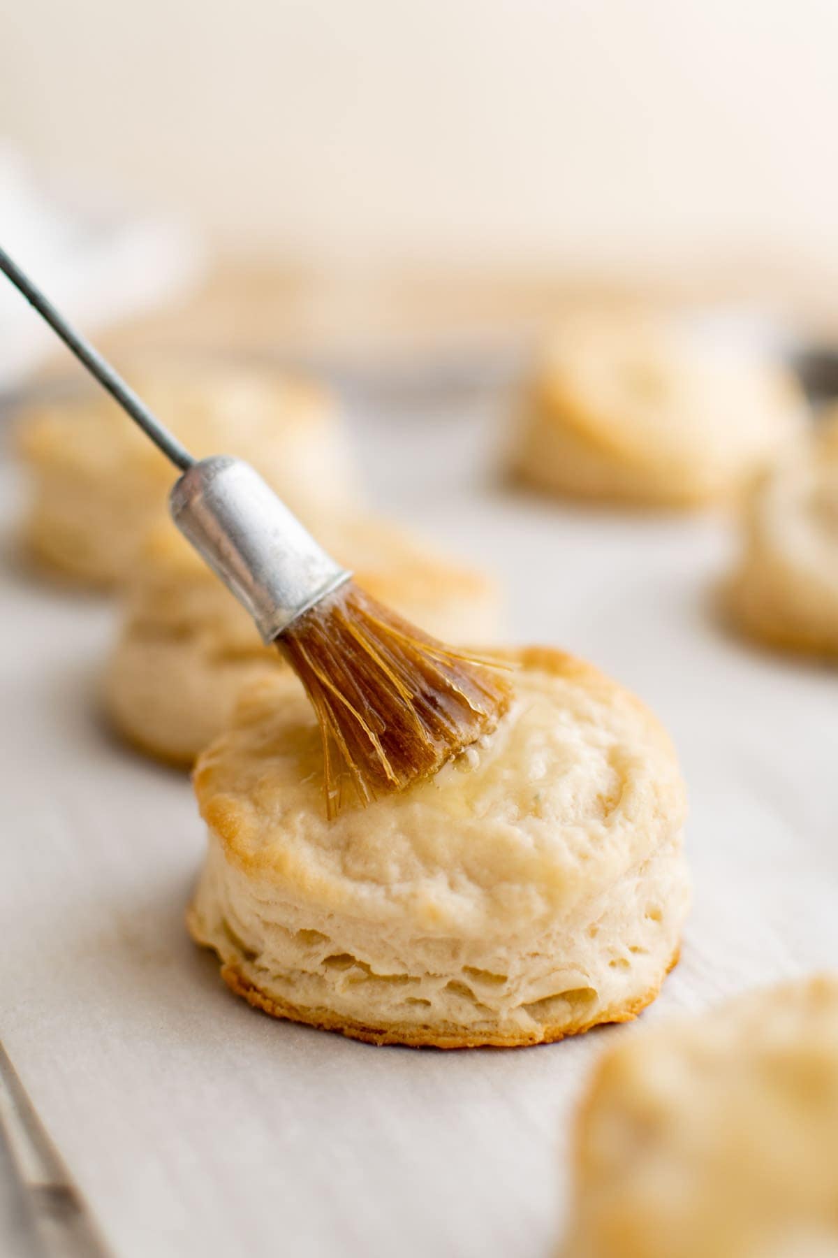 brushing butter on top of a biscuit