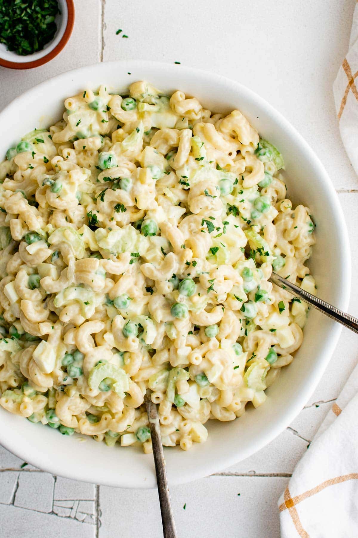 macaroni salad in a large white bowl with two serving spoons