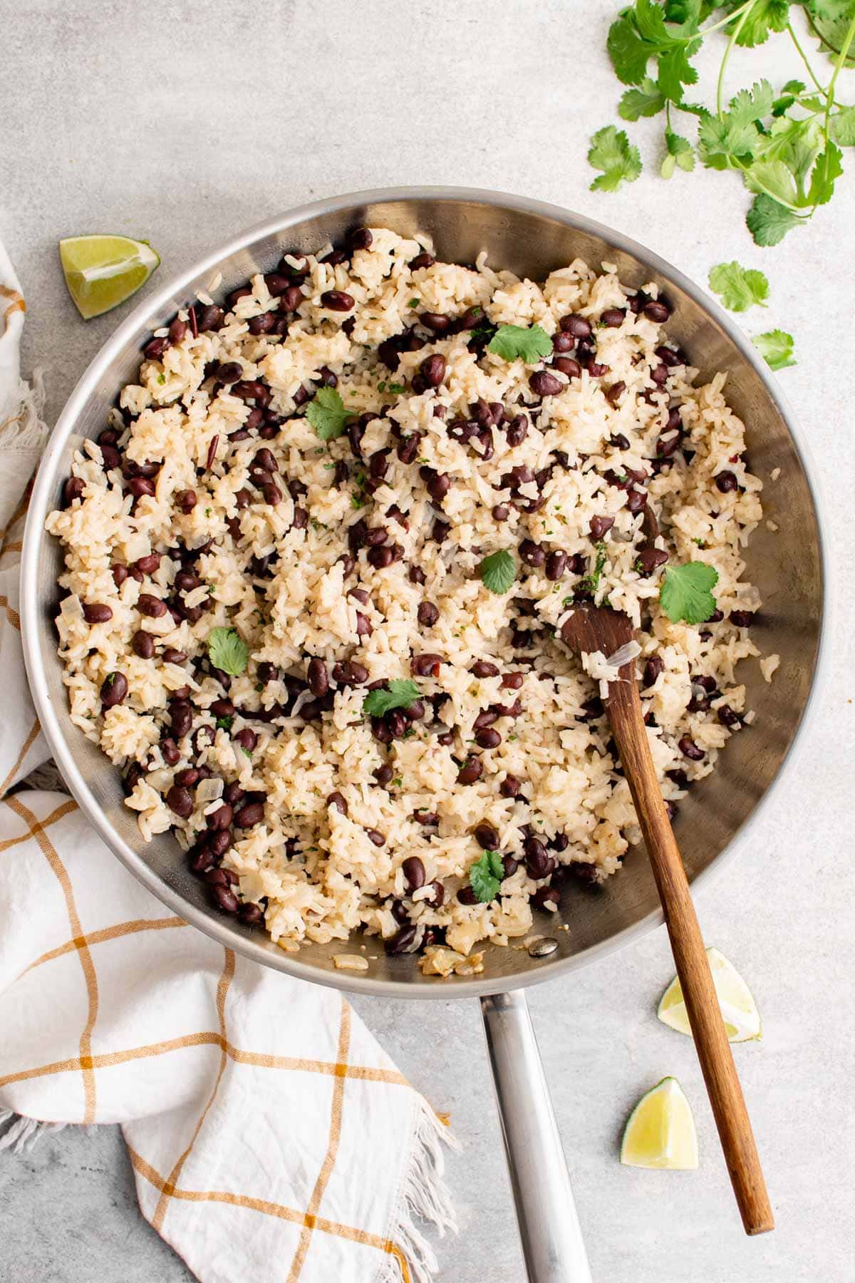 black beans and rice in a large skillet with a wooden spoon