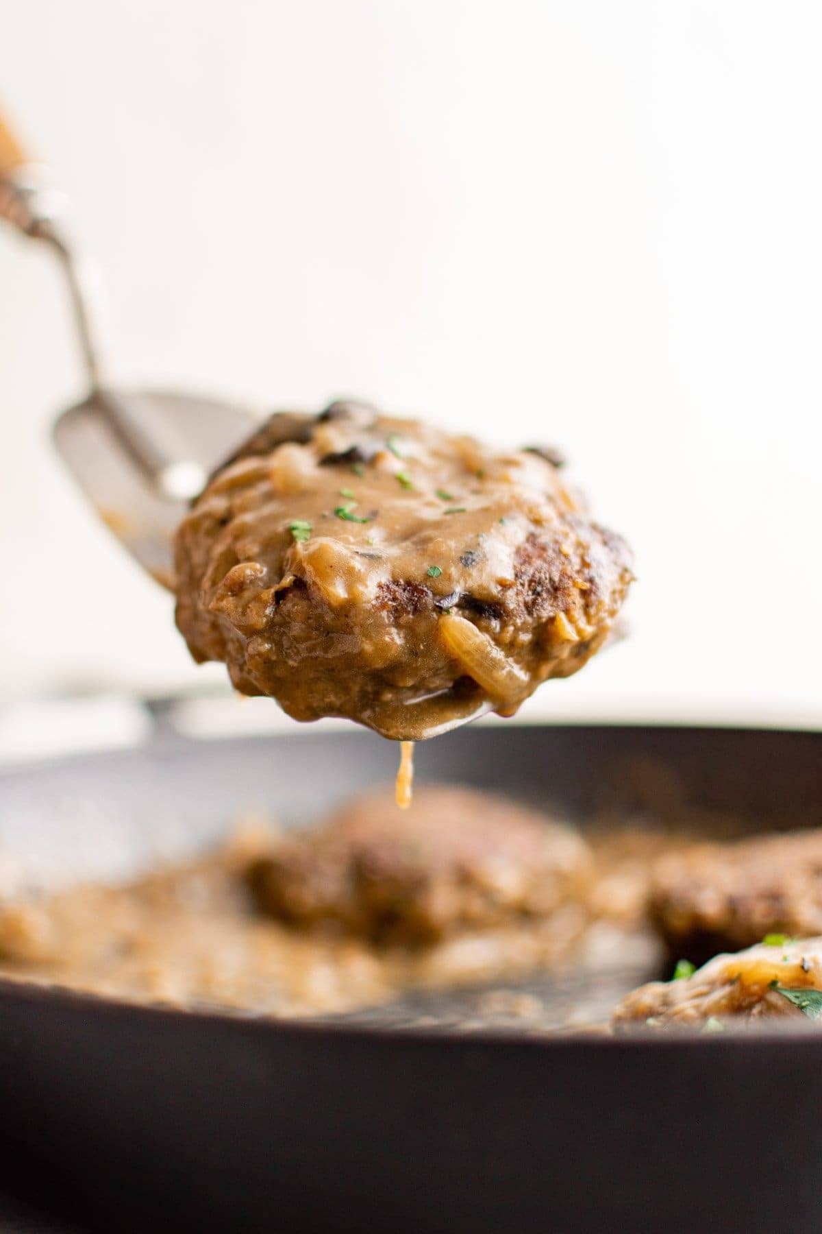 a spatula lifting a chopped steak from the skillet