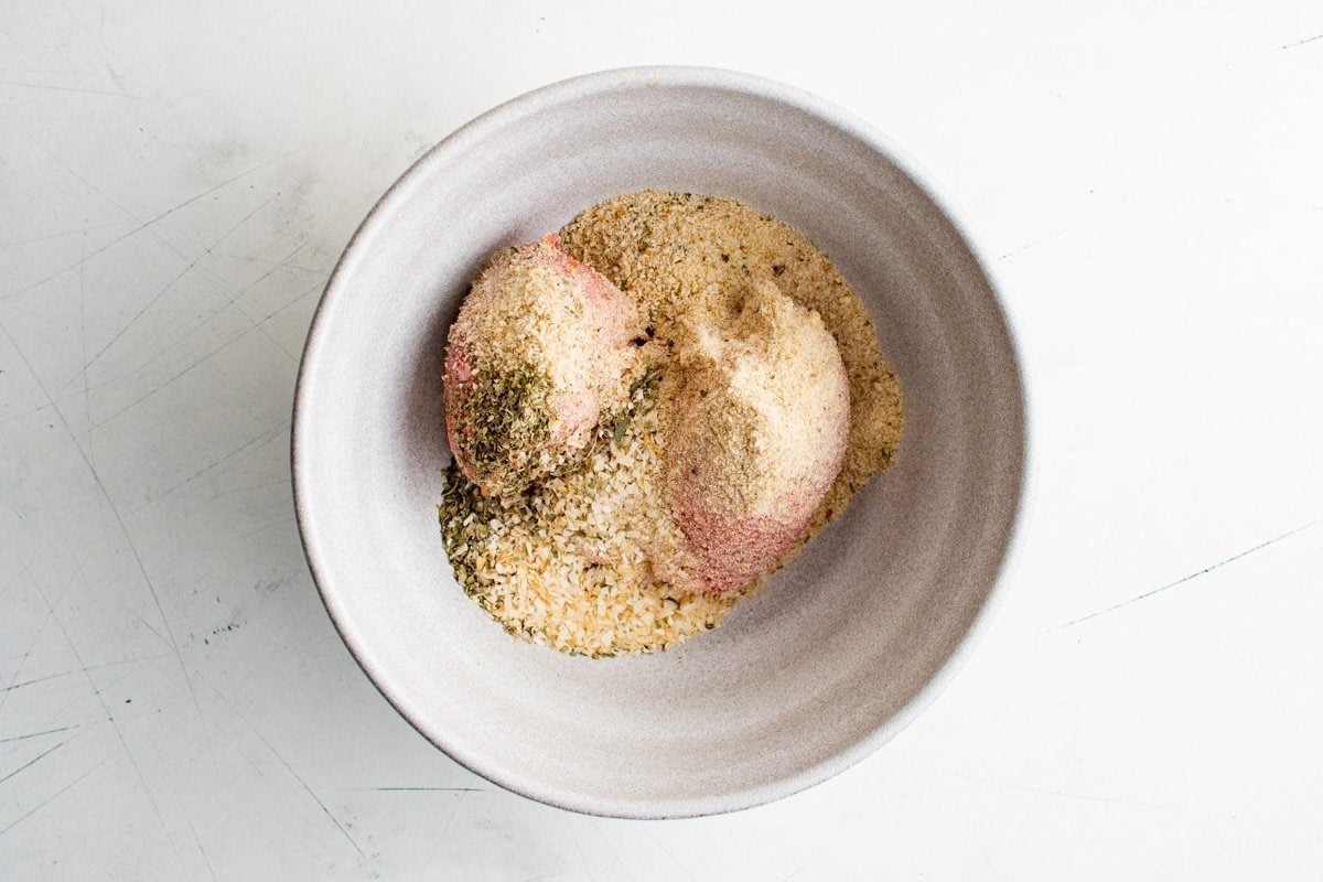 mixing meat and breadcrumbs and other meatloaf ingredients in a bowl