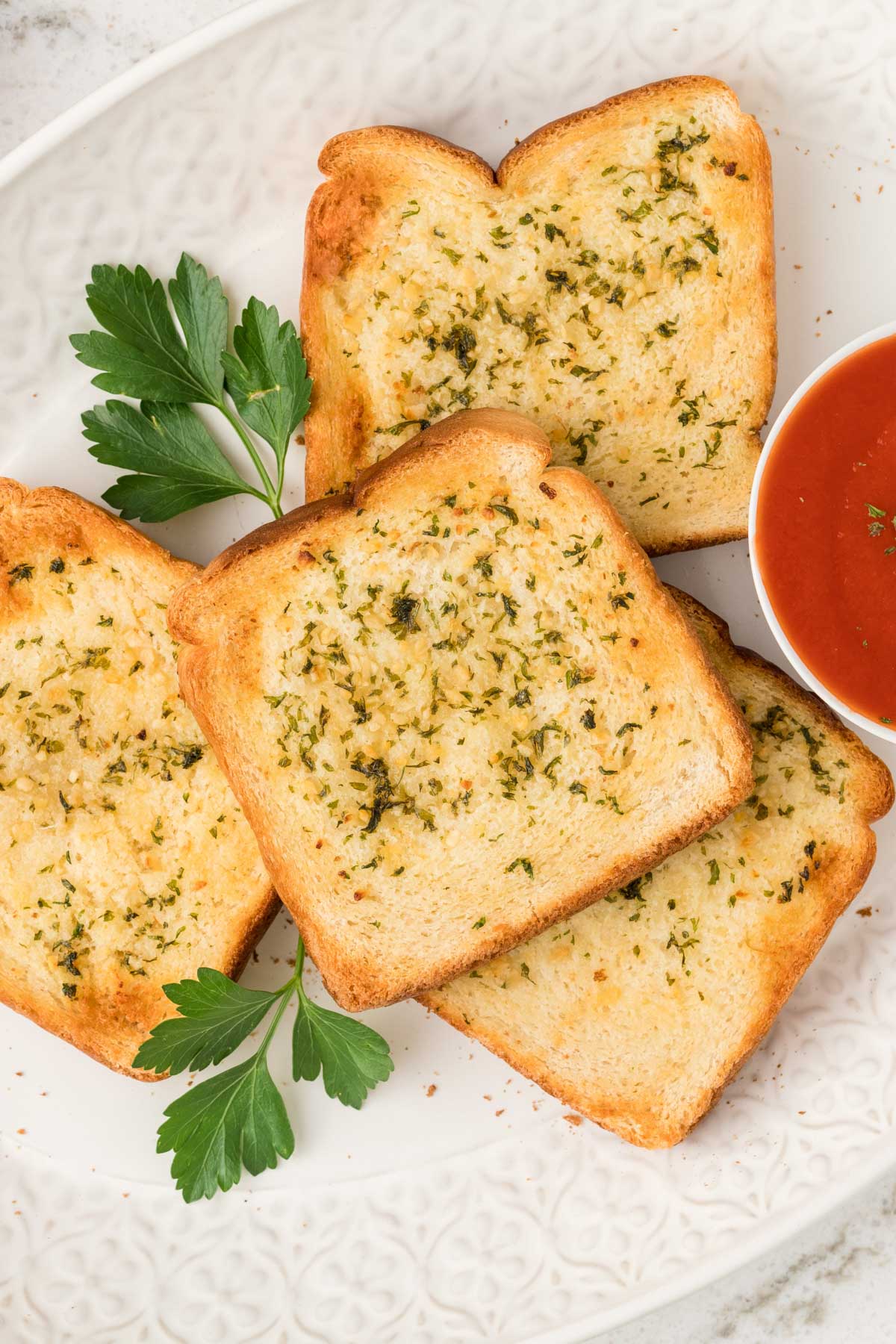 4 slices of Texas Toast garlic bread on a white plate with parsley leaves. 