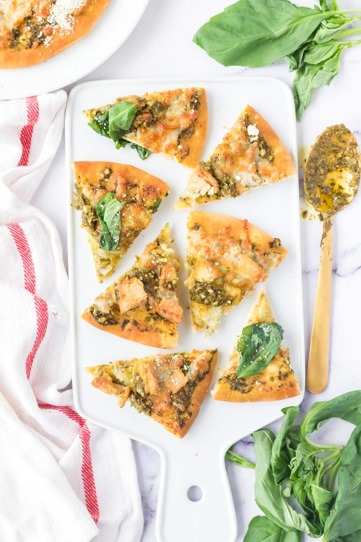 Slices of air fryer chicken pesto flatbread pizza on a white board.
