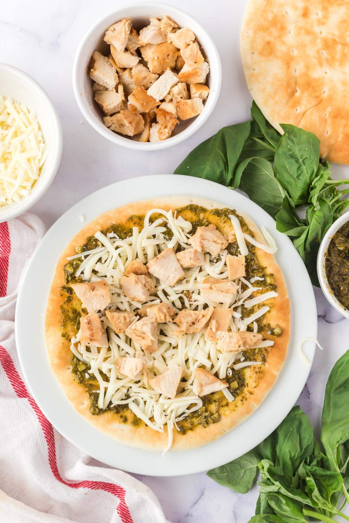 Uncooked air fryer chicken pesto flatbread on a plate.