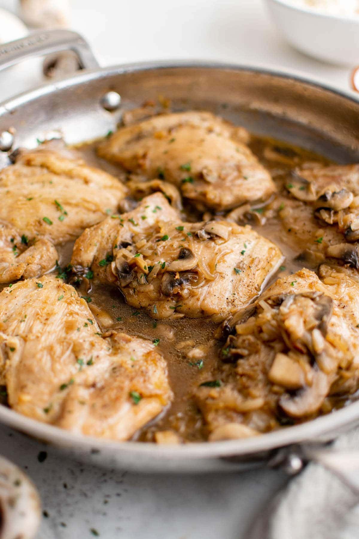 Skillet with chicken thighs in brown onion gravy.