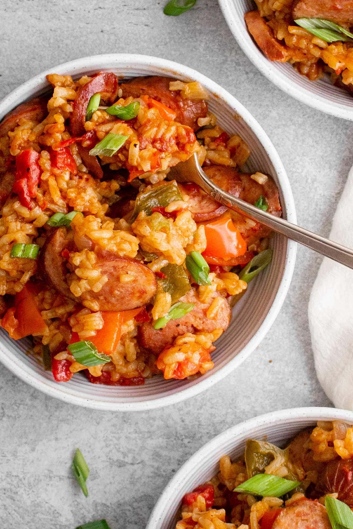 white bowl with cajun sausage and rice, and a fork.