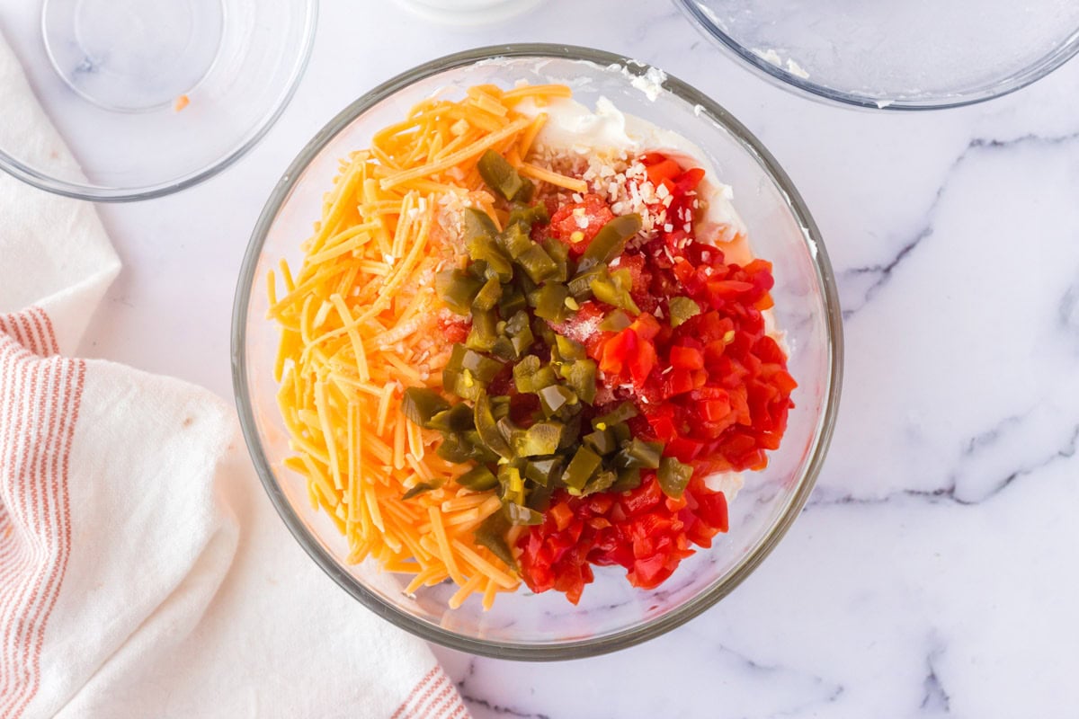 shredded cheese, pimento peppers and jalapenos in a bowl.