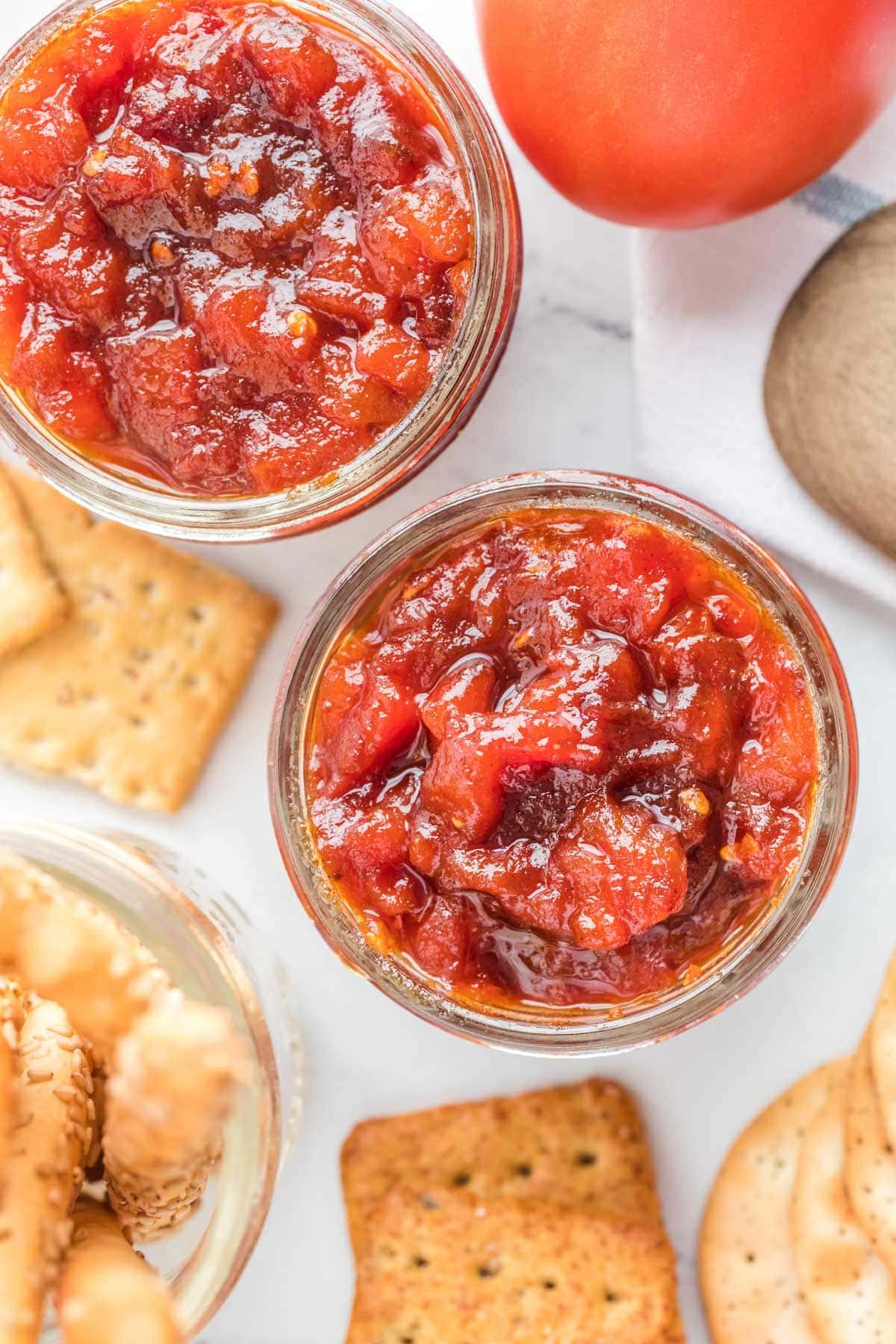 Tomato jam in small glass jars, with crackers.