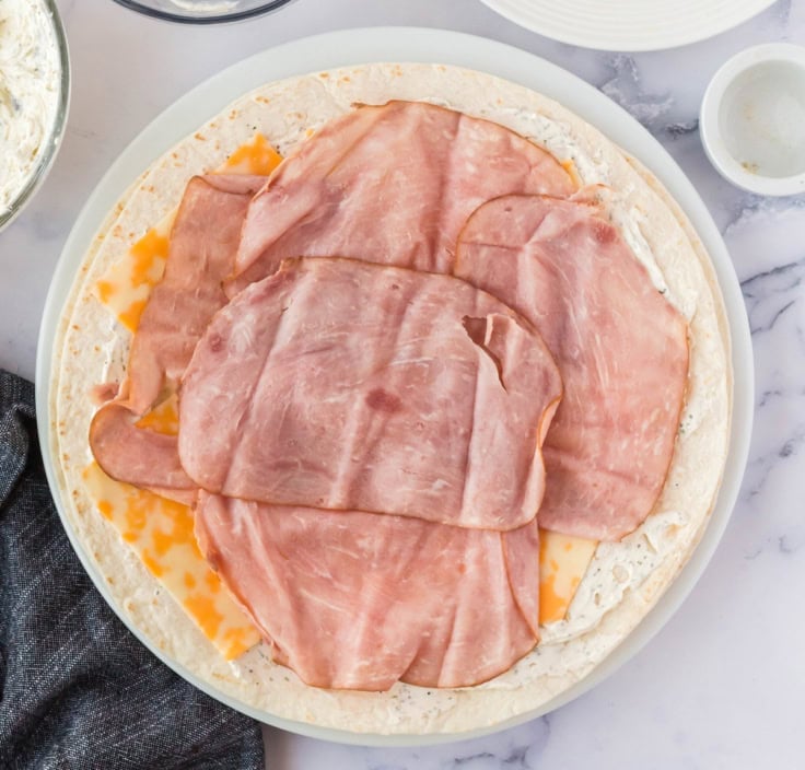 Slice ham and sliced cheese layered on a large tortilla.