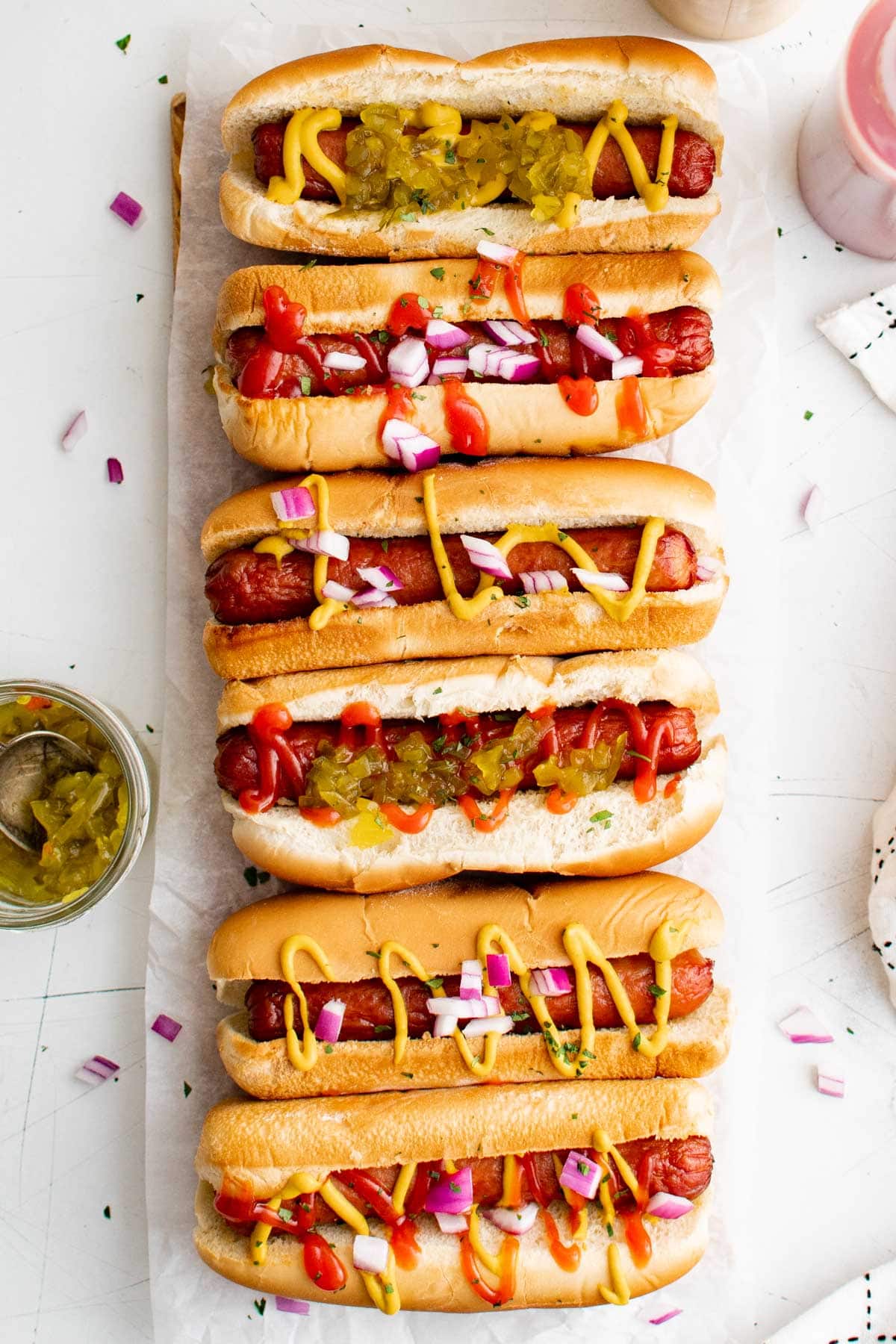 Air Fryer Hot Dogs lined up with toppings like relish and mustard.