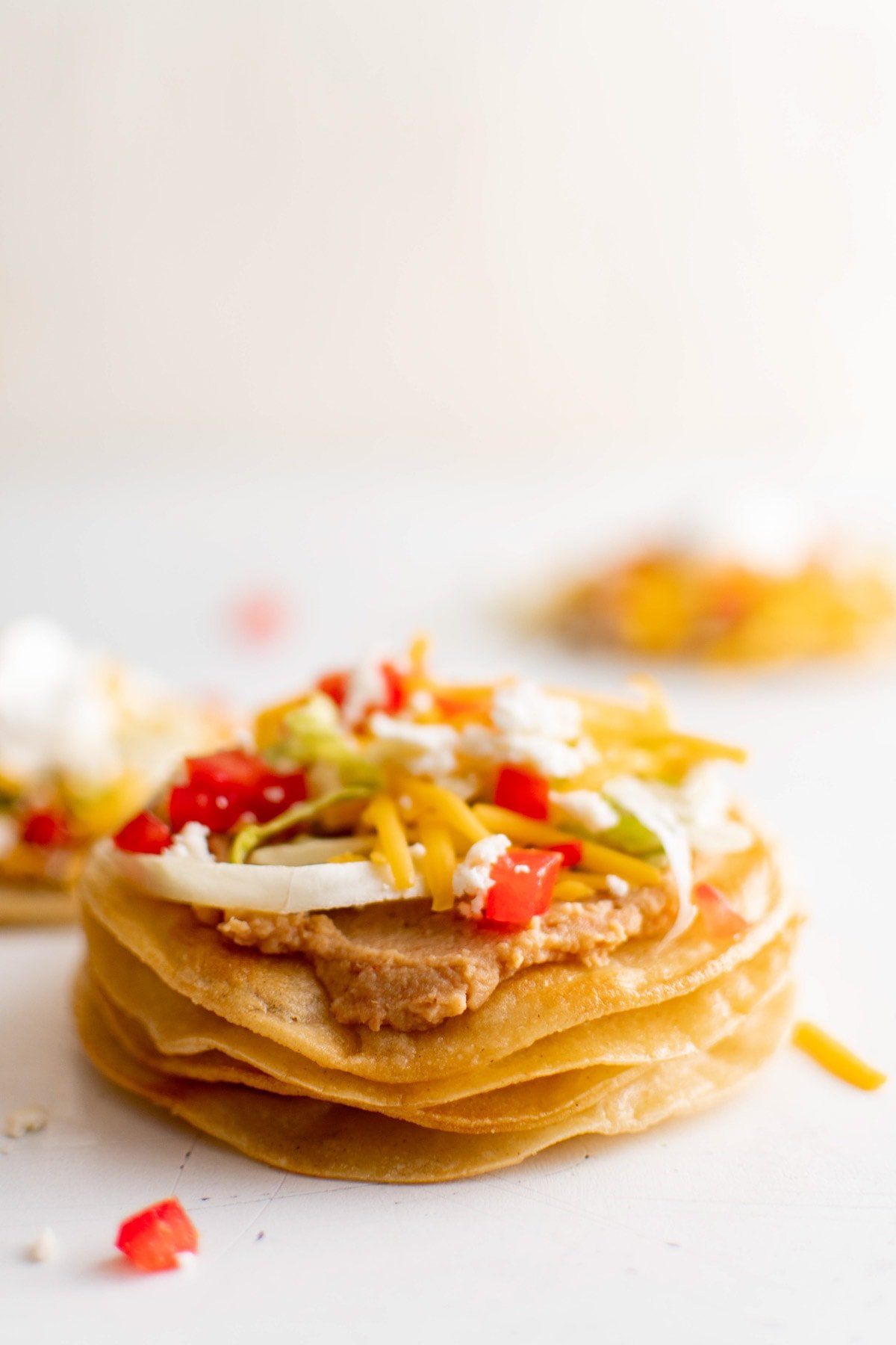 Baked tortilla shells stacked, with topping on the top one.