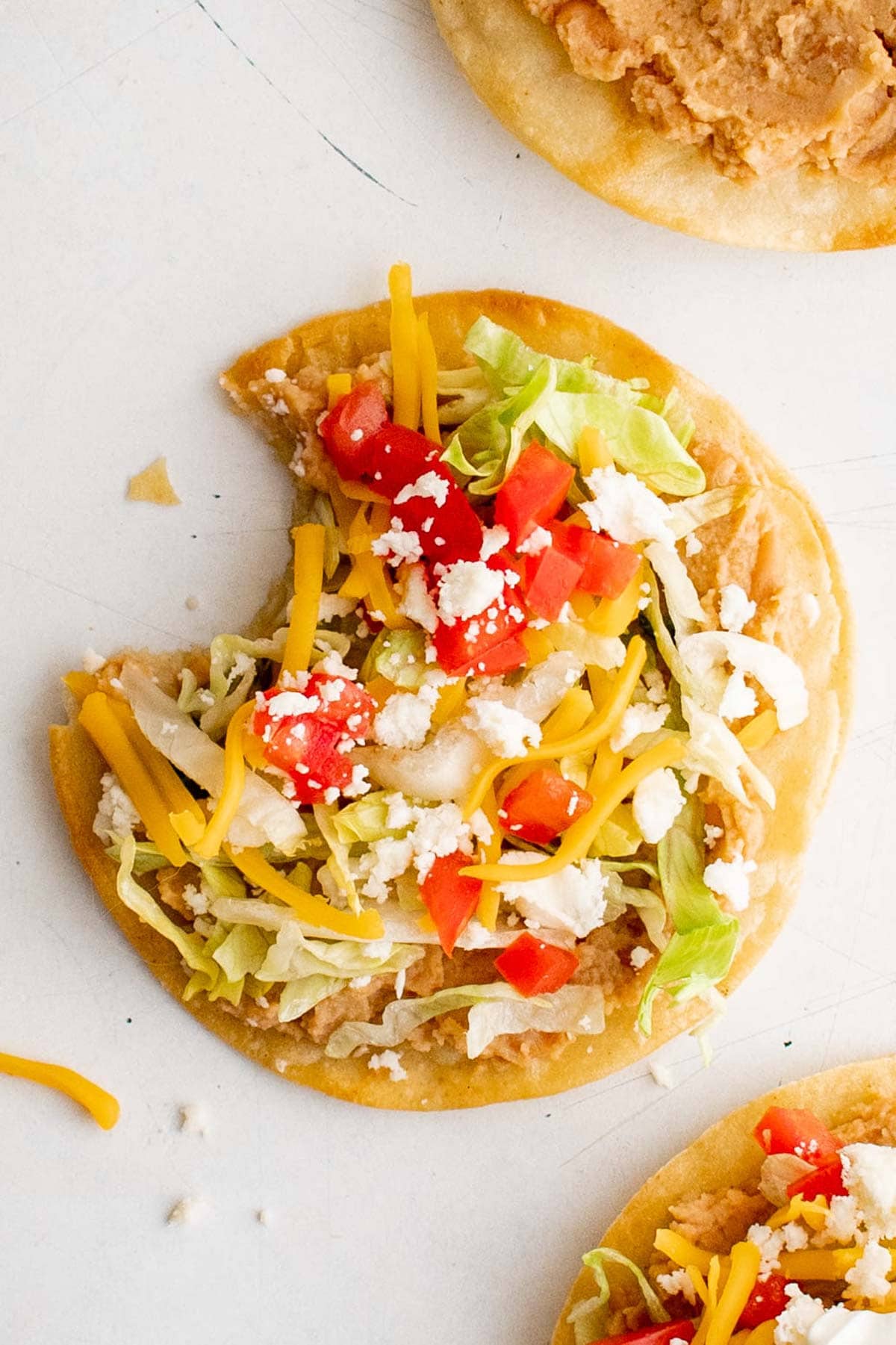 Loaded tostada with a bite taken out of it.