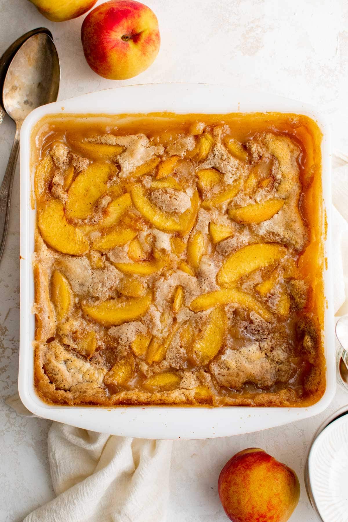 Peach cobbler in a white square baking dish.