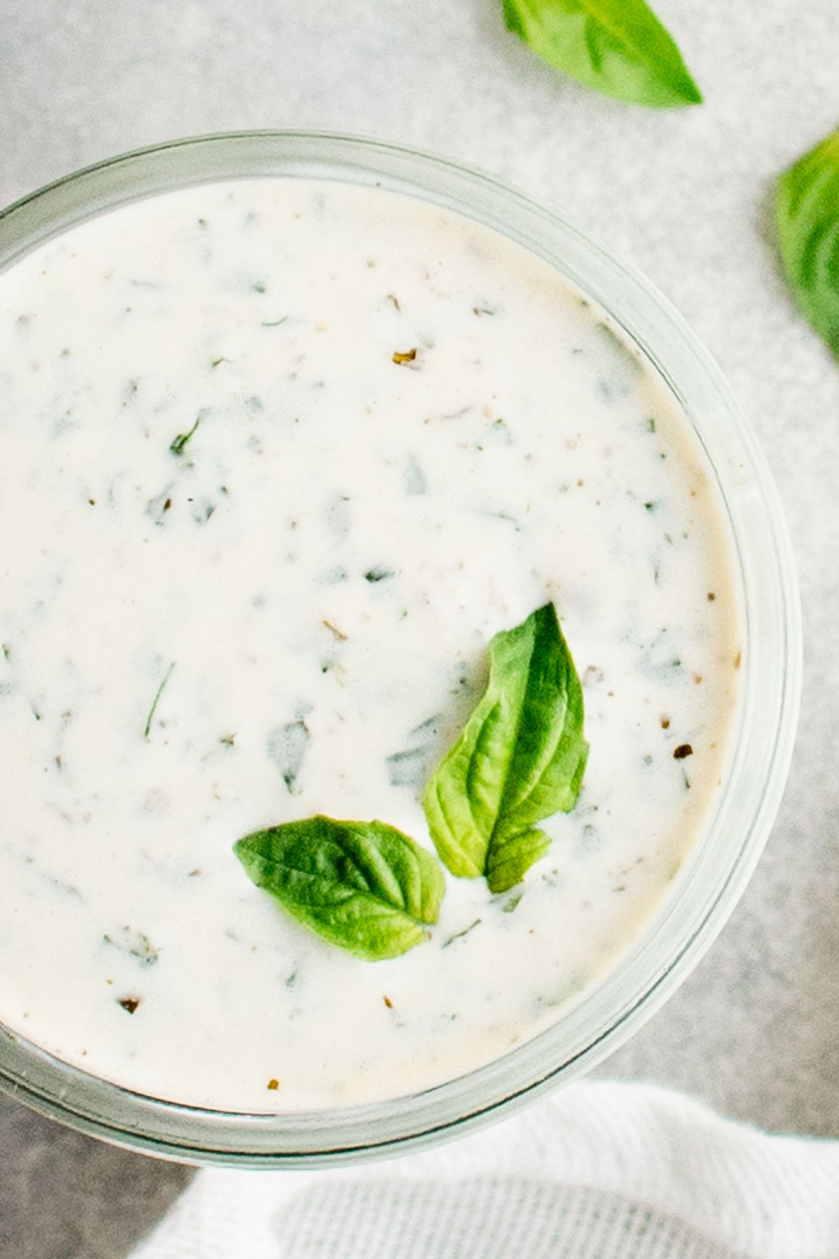 Green Goddess Dressing in a jar with basil leaves.