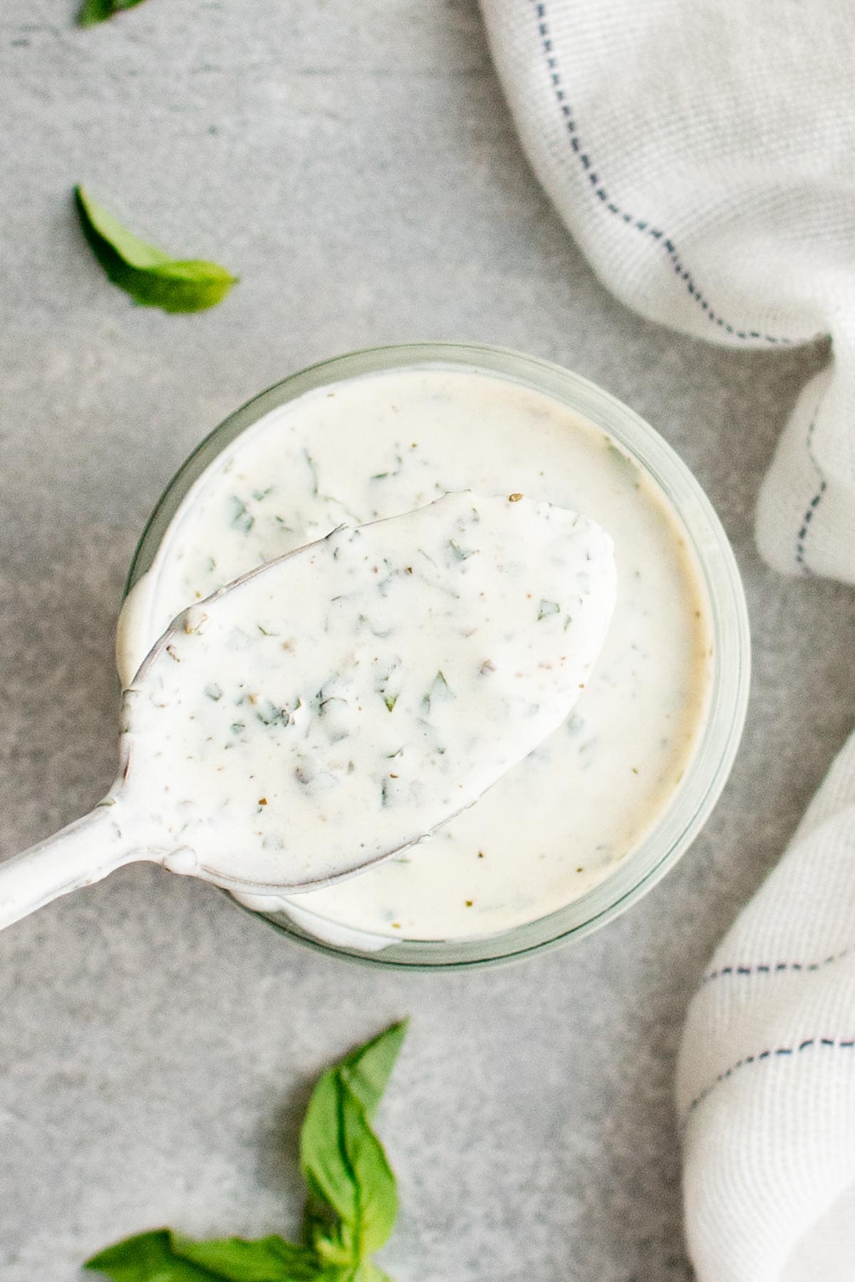 Green Goddess Dressing in a jar with a spoon. 