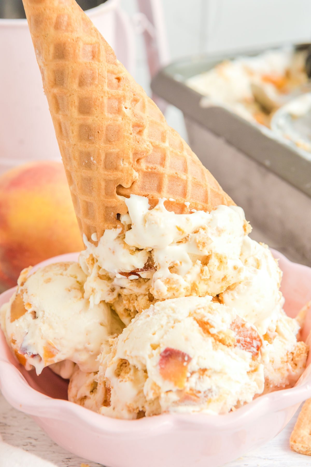 Peach ice cream in a bowl with a waffle cone.