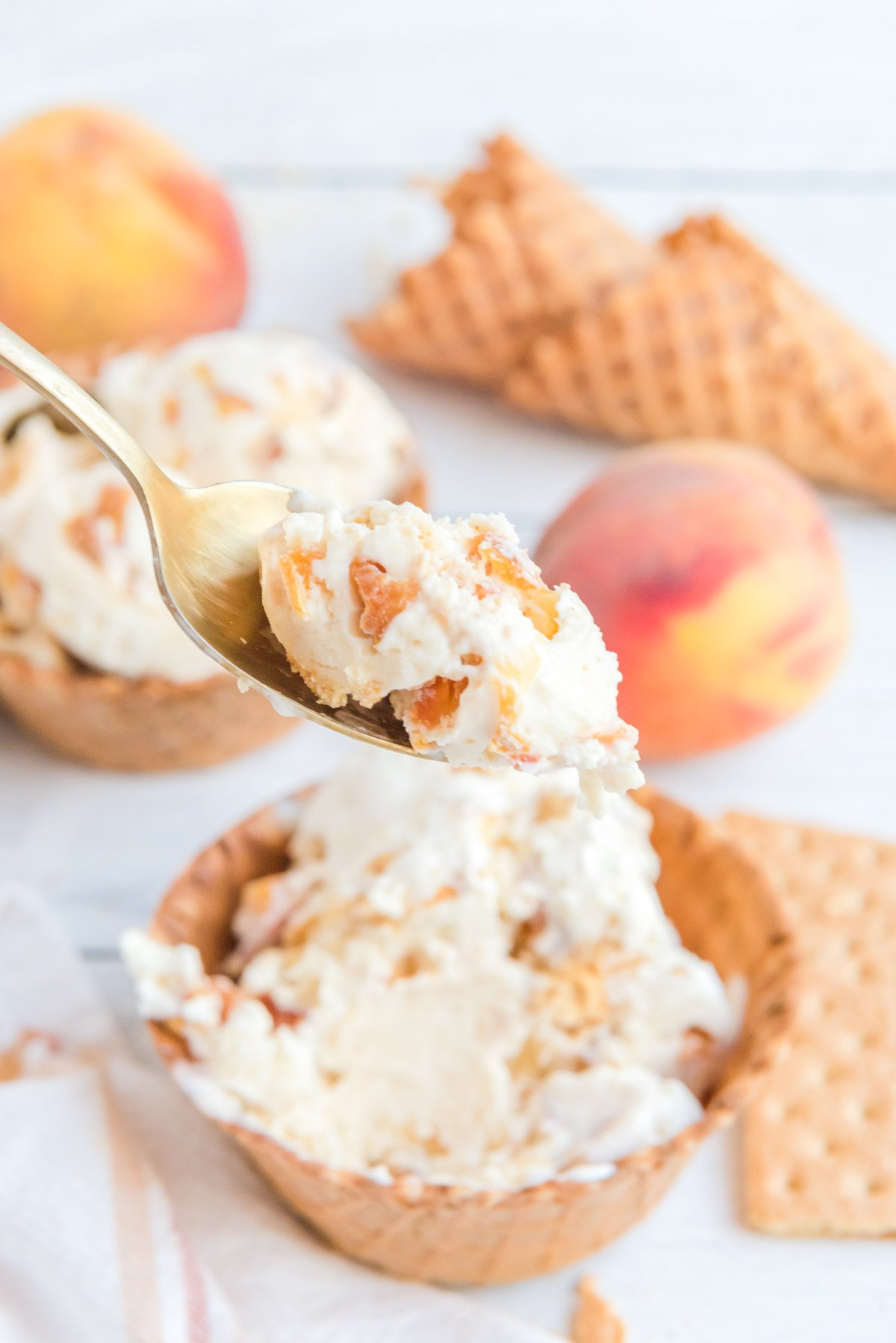 Peach ice cream in a waffle bowl and a spoon.