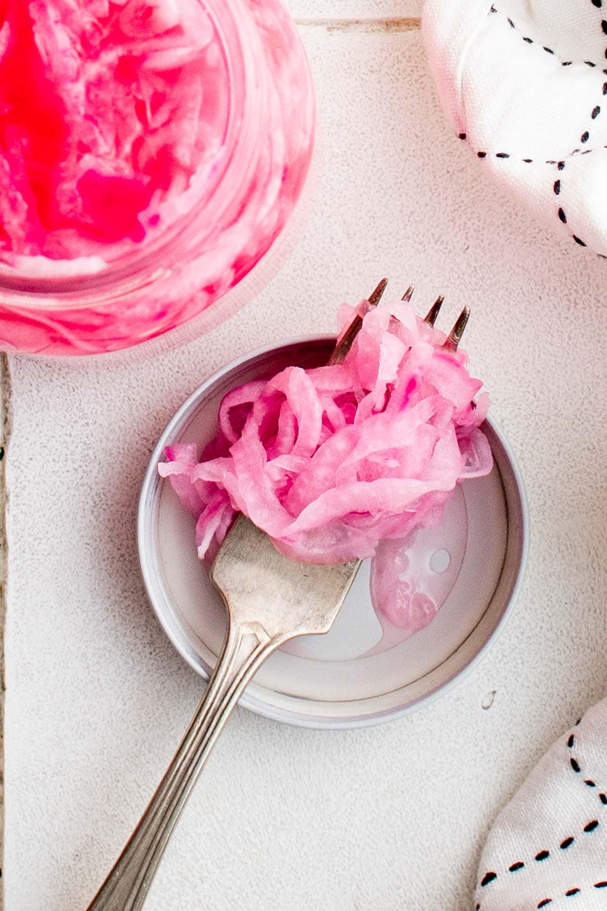 Pickled red onions in a jar and on a fork.