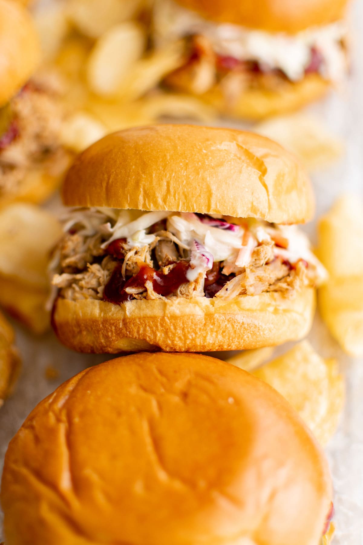 Pulled pork sandwiches with coleslaw and chips. 