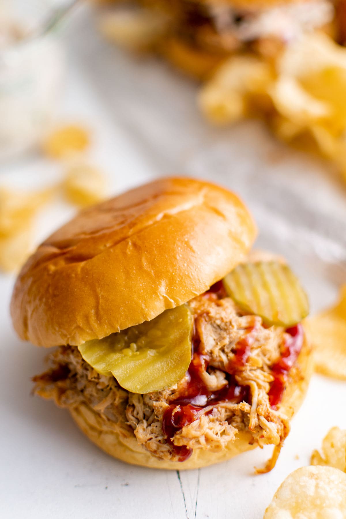 Pulled pork sandwich with bbq sauce and pickles.