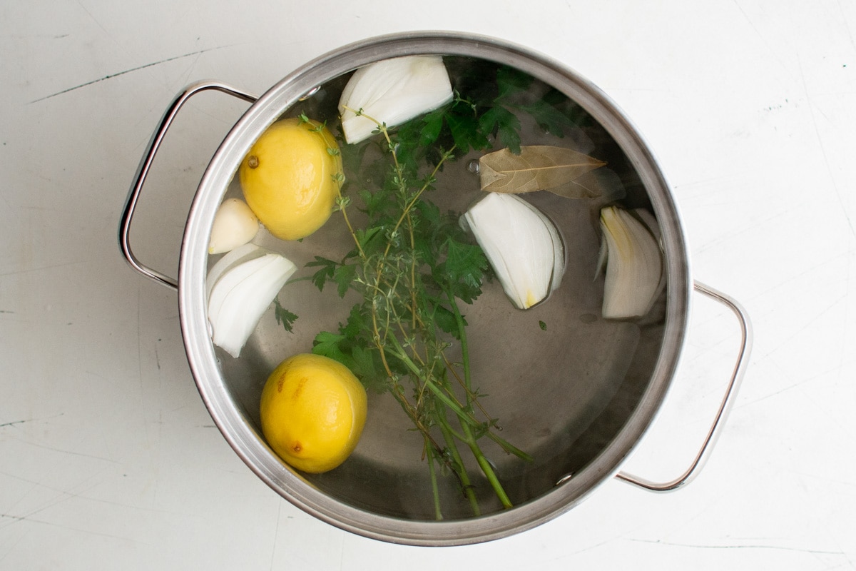 Soup pot with water, lemons, onions and herbs. 