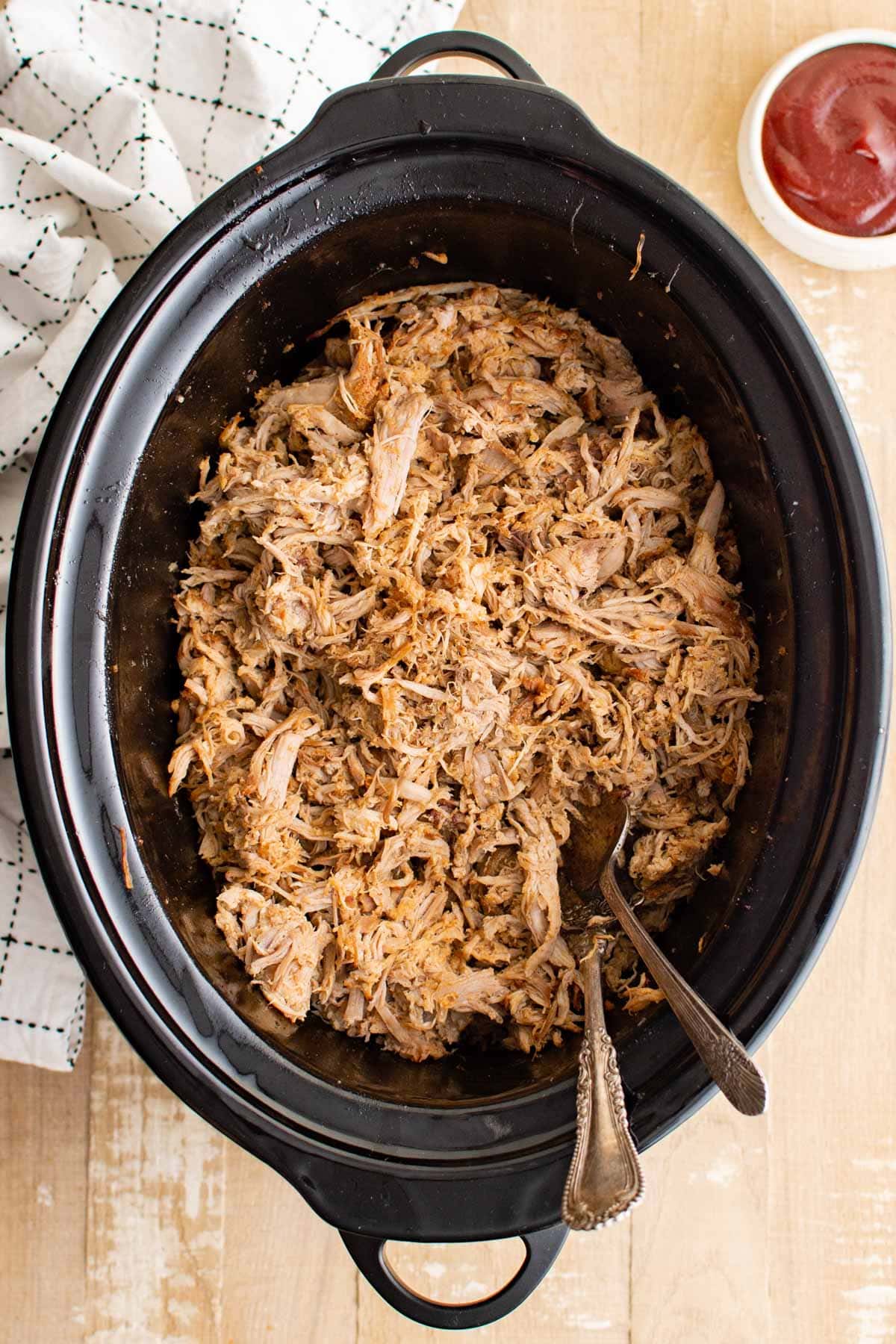 Pulled pork shredded in a slow cooker pot. 