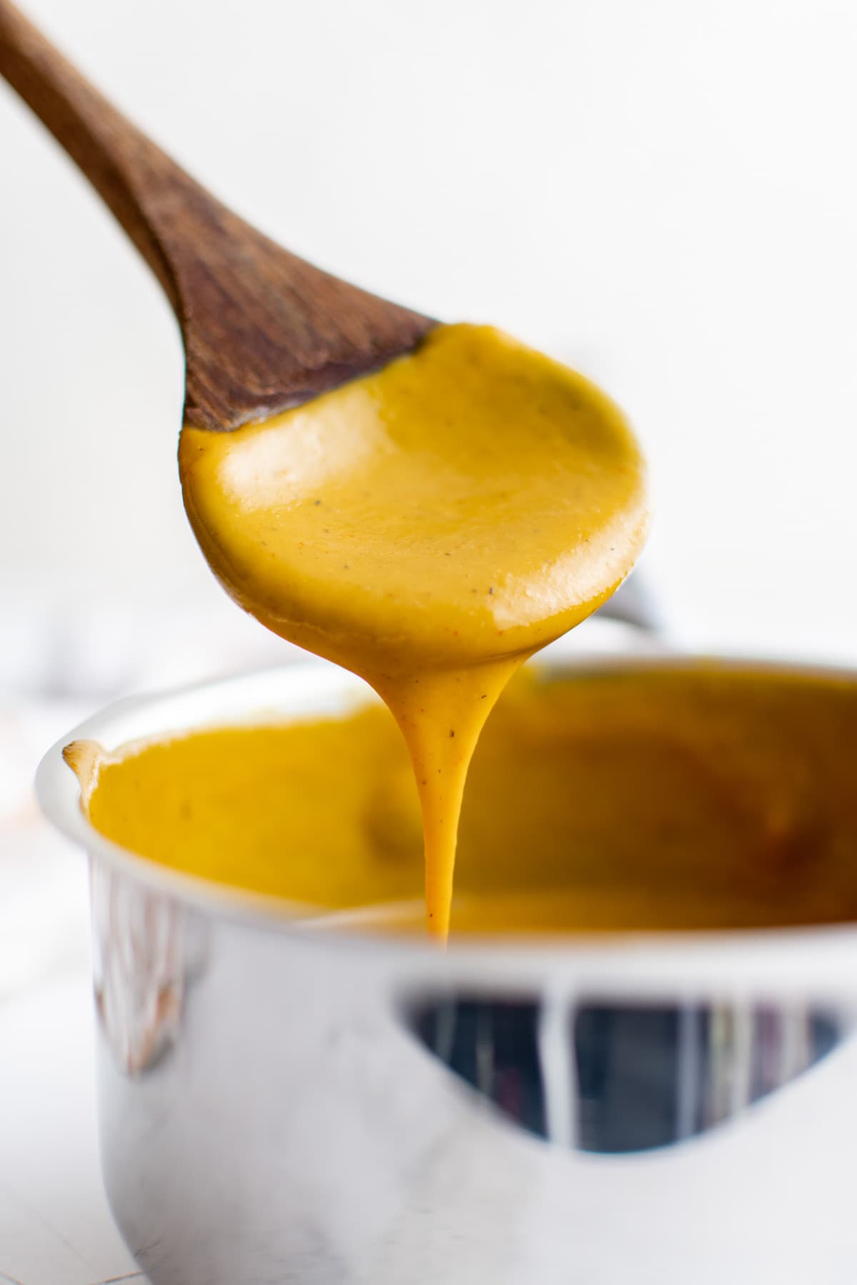 Carolina bbq sauce in a saucepan with a wooden spoon.